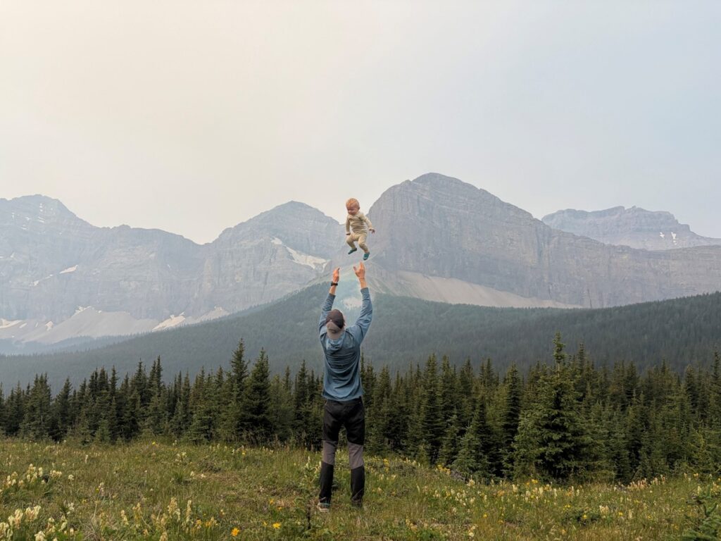 father tossing a baby in the air in the mountains