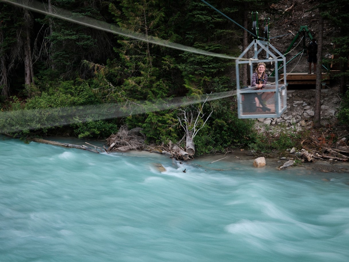 a hiker in a cable car across a river